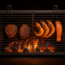Grilled meat, shrimp, and salmon on a barbecue grill with flames below.