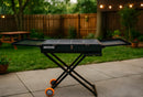 Portable grill on a stand in a backyard setting